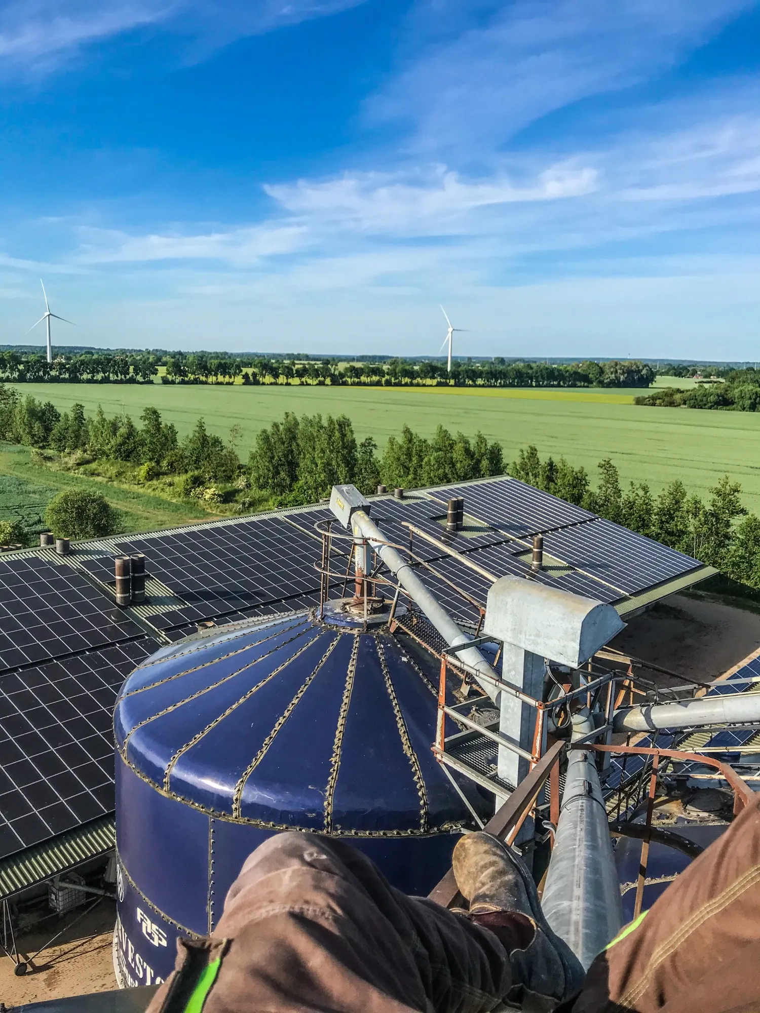 Photovoltaikanlage auf einem Stalldach, Windräder am Horizont