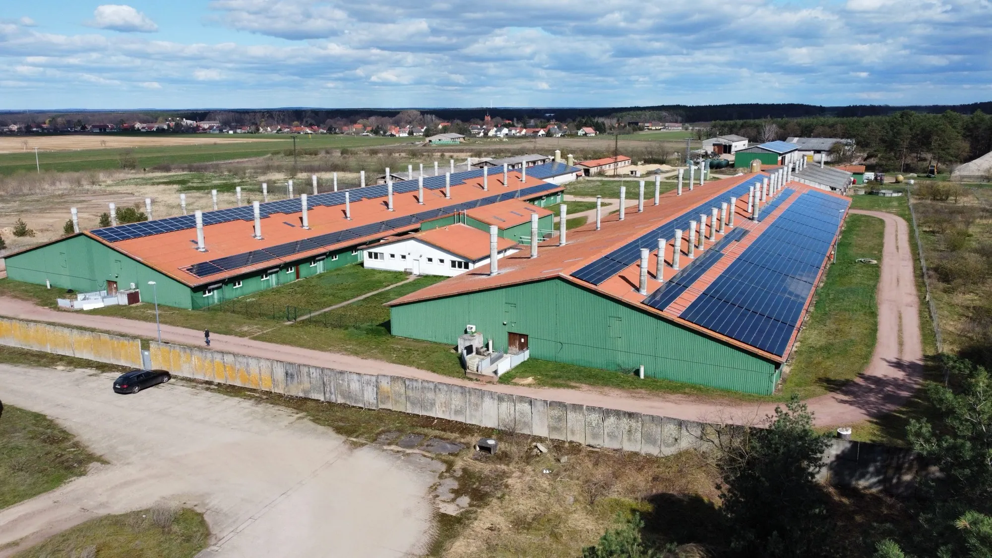 Luftaufnahme der Stallanlagen, die Dächer teilweise mit Photovoltaik belegt